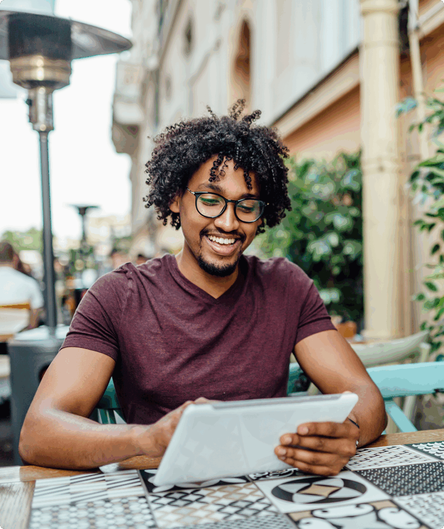 Man smiling while using tablet outdoors.