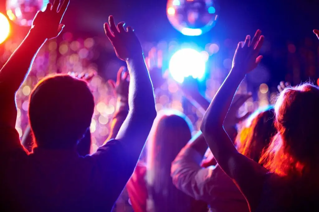 People dancing under colorful lights at party.
