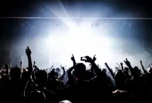 Concert crowd with raised hands and lights.