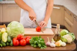 Person chopping tomato on kitchen counter.
