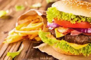 Burger with fries on wooden table.