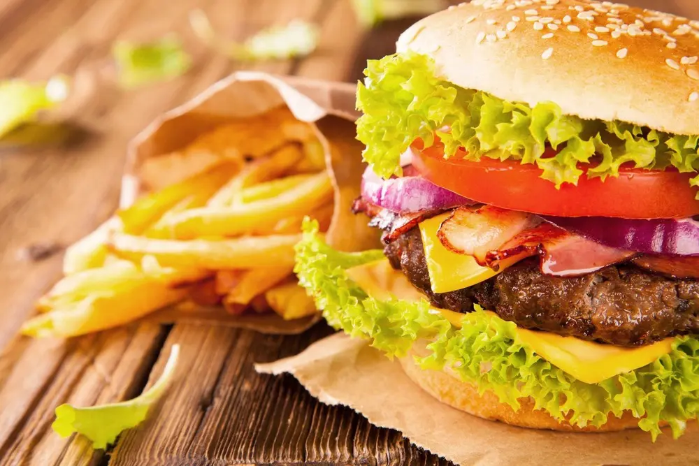 Burger with fries on wooden table.