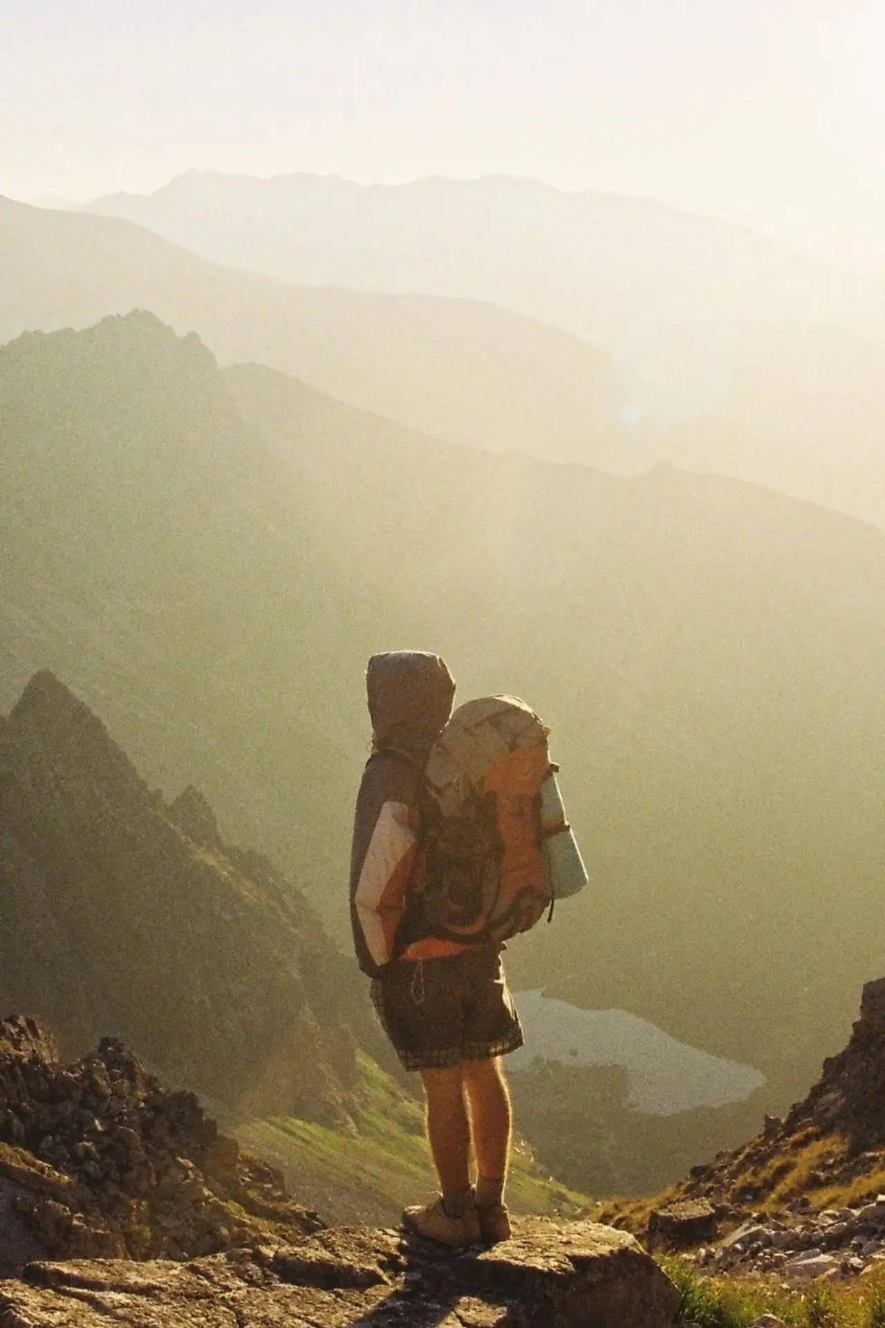 Hiker standing on mountain ridge at sunrise.
