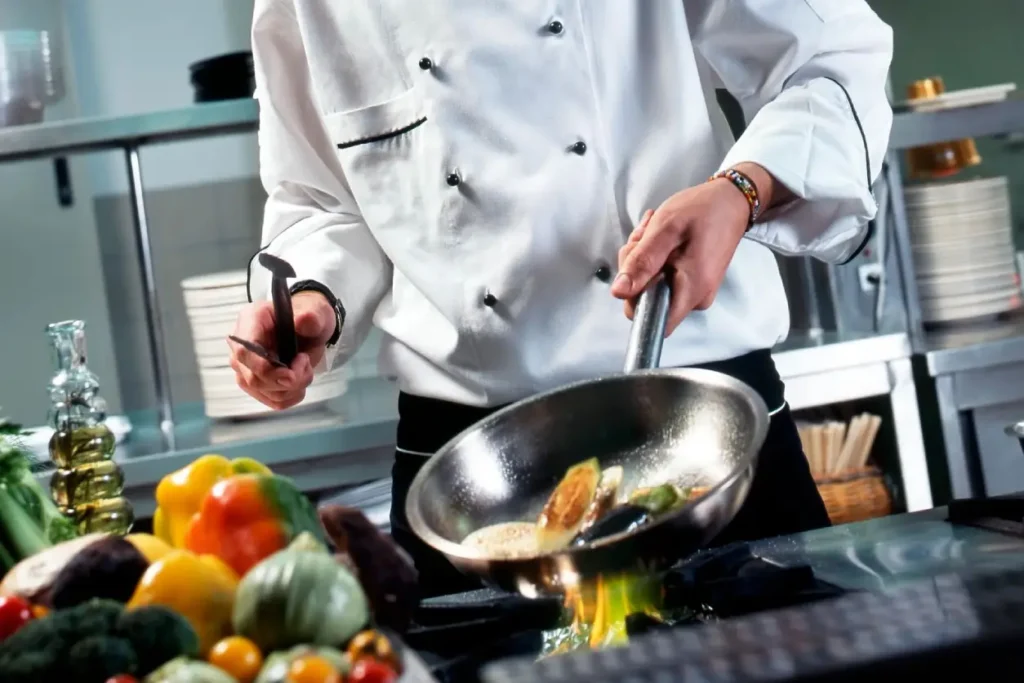 Chef cooking vegetables in a professional kitchen.